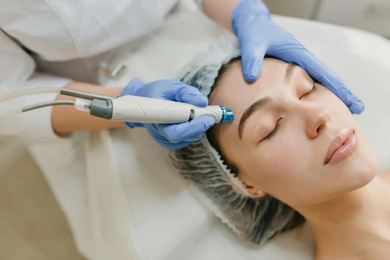 Una paciente tumbada recibe un tratamiento facial de manos de una médica
